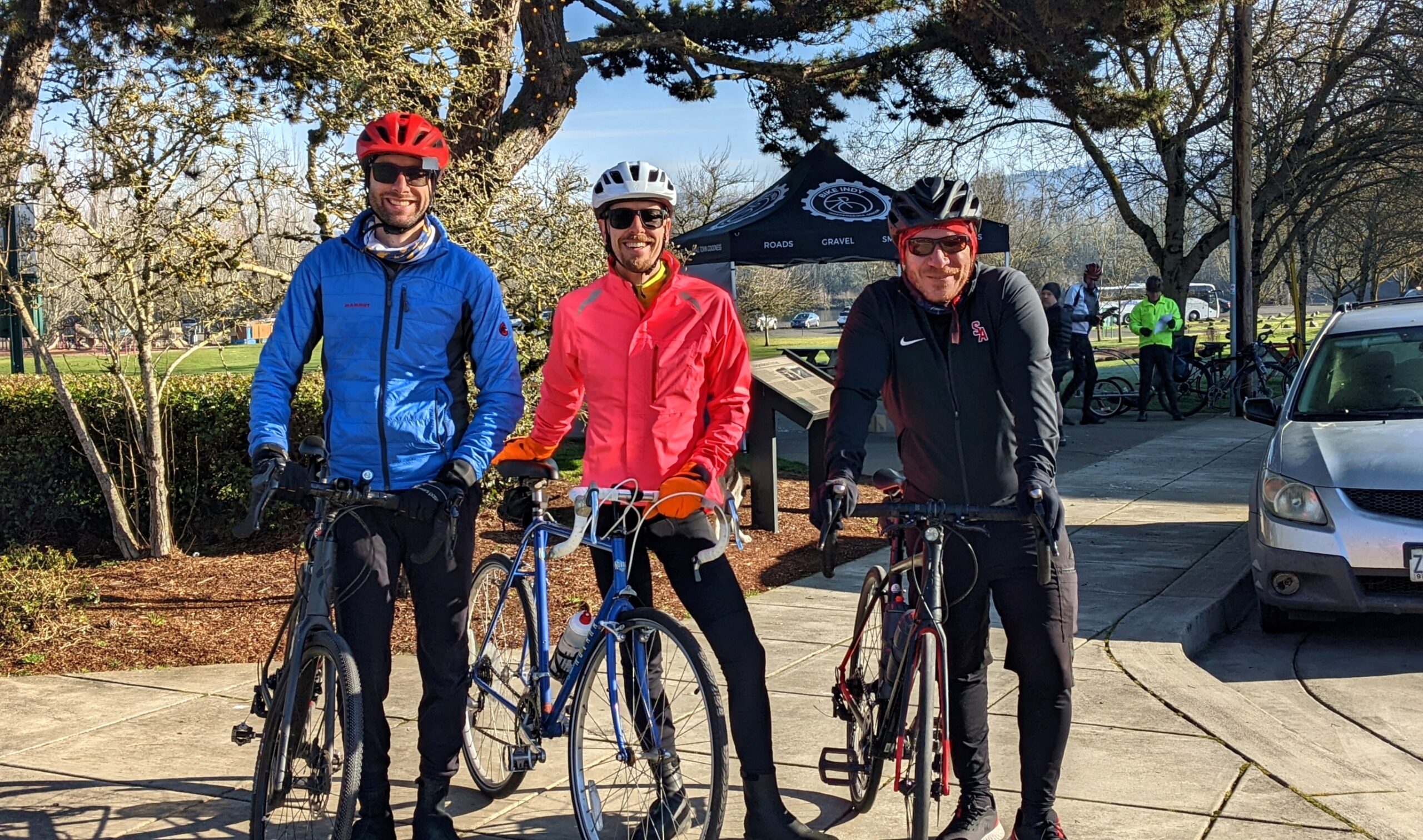 A group of 3 male bicyclists standing in front of and looking at the camera.