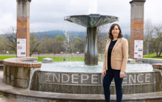 mayor kate schwarzler smiling and standing in front of a water fountain that says "Independence"