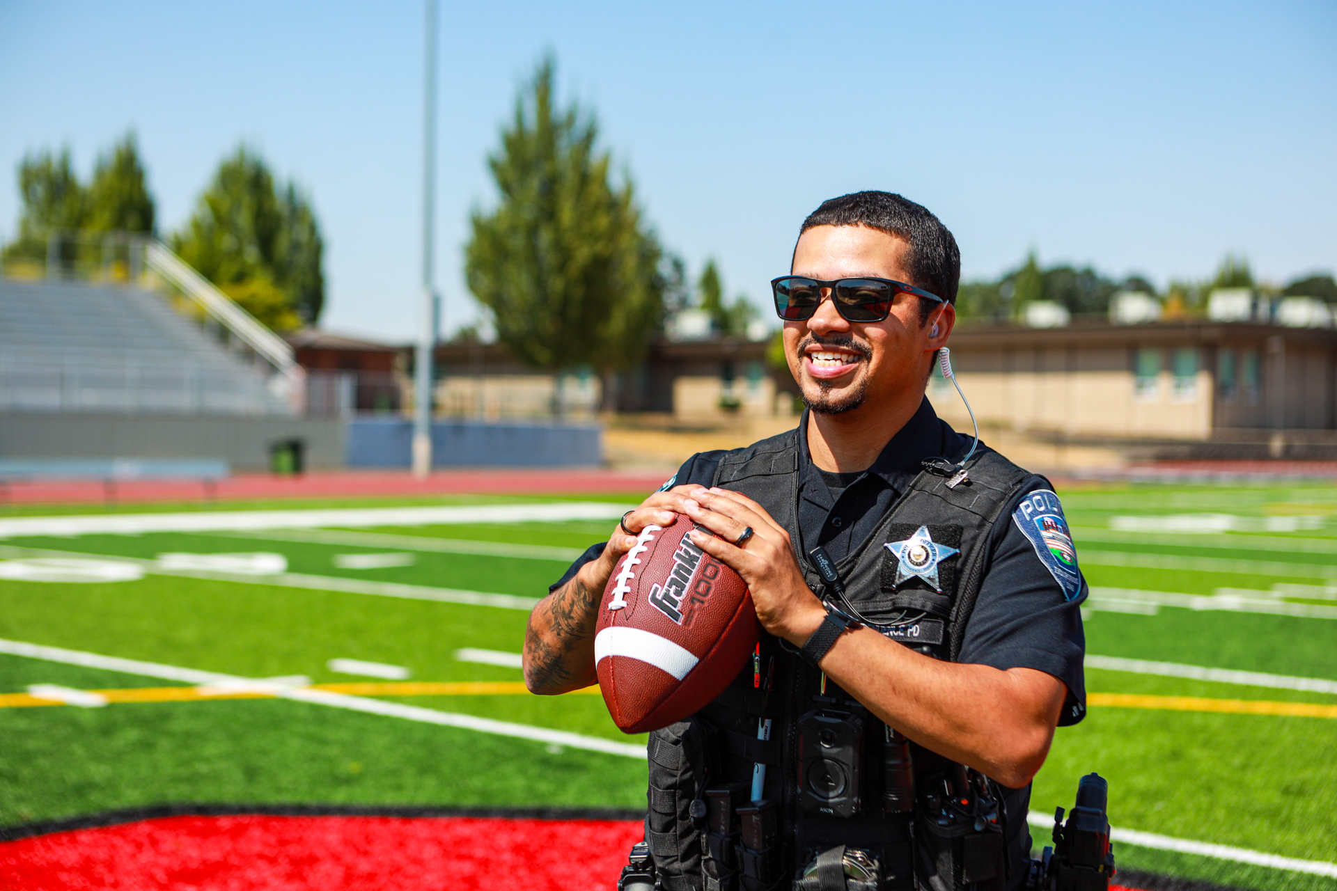 officer preston smiling on a football field and holding a football