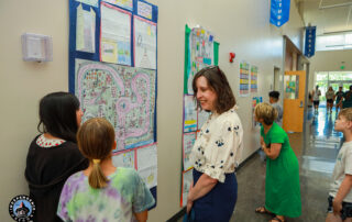 Visitors admire colorful student artwork displayed on walls during an educational event in a school hallway.