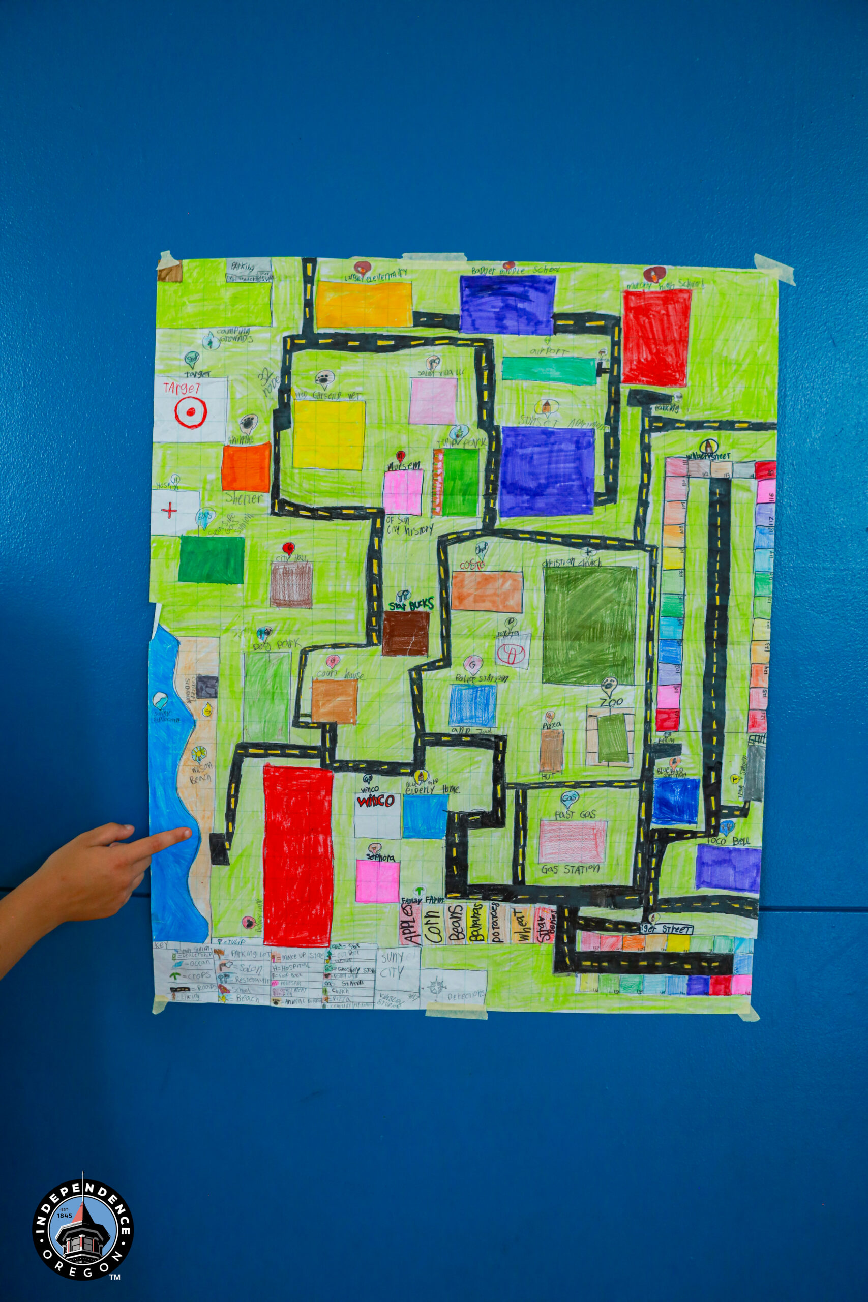 Colorful hand-drawn map featuring various locations, roads, and landmarks on a blue wall background.